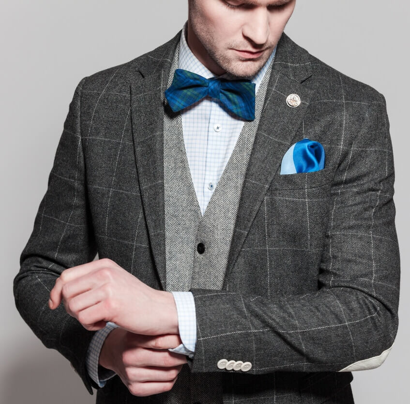a picture of a man in blue bow tie and light grey cardigan and charcoal grey checkered suit image on richardsclothing.ca Premium fashion men's clothing store in London ON